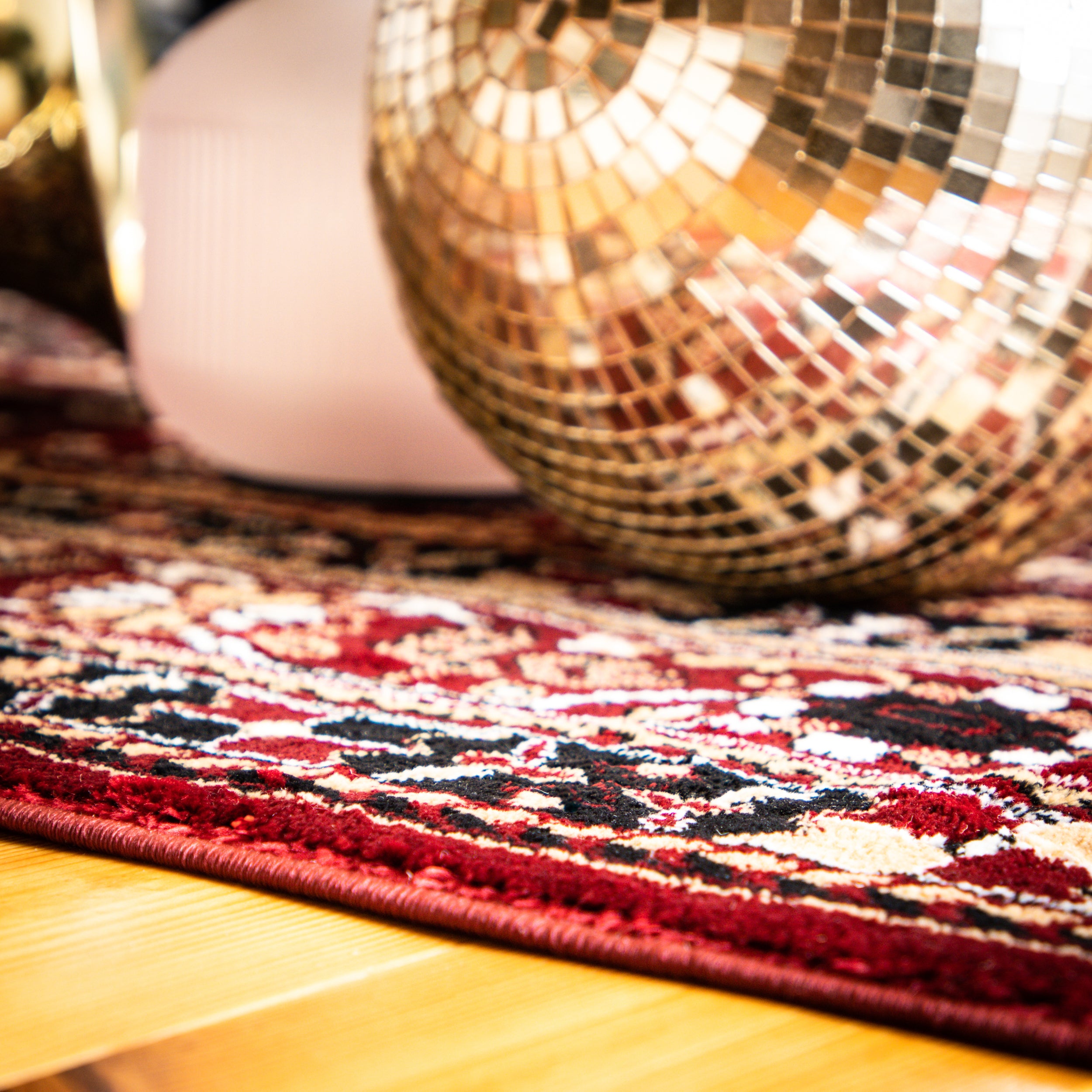 Ein Discokugel auf einem Teppich, die das Licht in glitzernden Reflexionen streut.